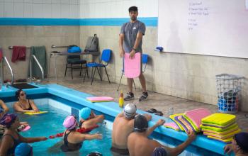 Profesor de natación entrega instrucciones a las personas funcionarias que participan del taller AFI